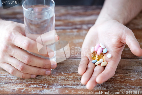 Image of close up of male hands holding pills and water