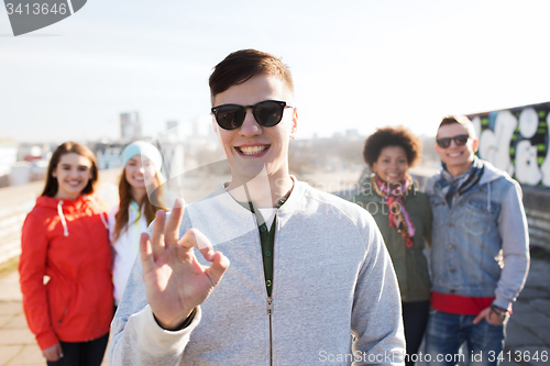 Image of happy teenage friends showing ok sign on street