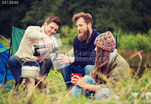 Image of group of smiling friends cooking food outdoors