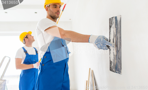 Image of two builders with painting tools repairing room