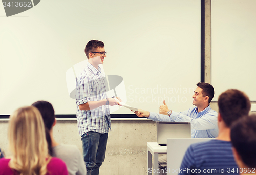 Image of group of students and smiling teacher with notepad