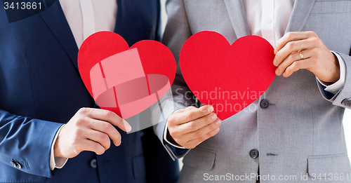 Image of close up of male gay couple holding red hearts