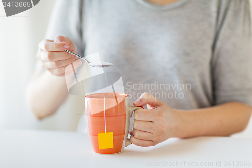 Image of close up of woman adding sugar to tea cup