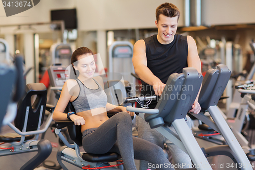 Image of happy woman with trainer on exercise bike in gym