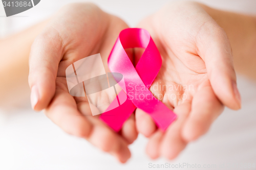 Image of close up of hands and pink cancer awareness ribbon