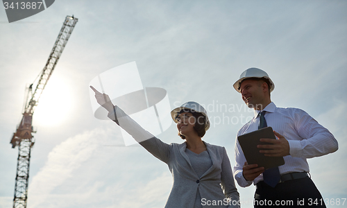 Image of happy builders in hardhats with tablet pc outdoors