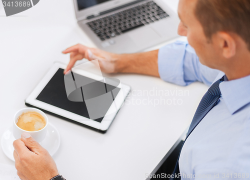 Image of businessman with tablet pc and coffee in office