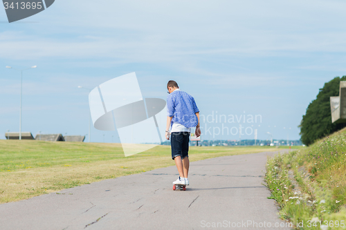 Image of man with longboard or skateboard riding on road