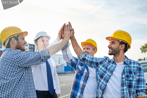 Image of close up of builders in hardhats making high five