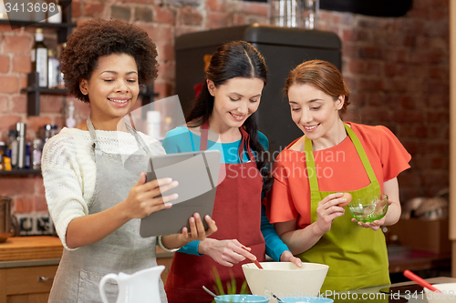 Image of happy women with tablet pc cooking in kitchen