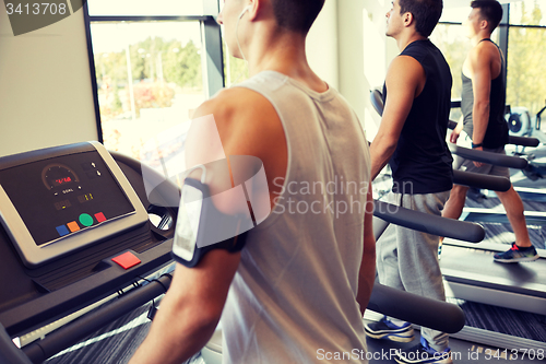 Image of smiling men exercising on treadmill in gym