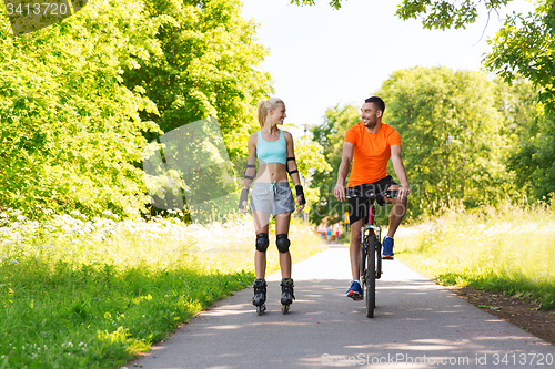 Image of happy couple with roller skates and bicycle riding