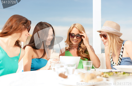 Image of smiling girls looking at tablet pc in cafe