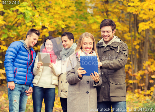 Image of group of smiling friends with tablets in park