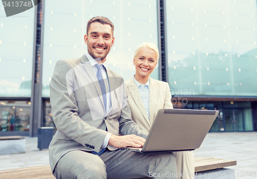 Image of smiling businesspeople with laptop outdoors