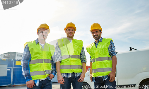 Image of happy male builders in high visible vests outdoors