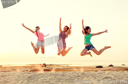 Image of smiling teen girls jumping on beach
