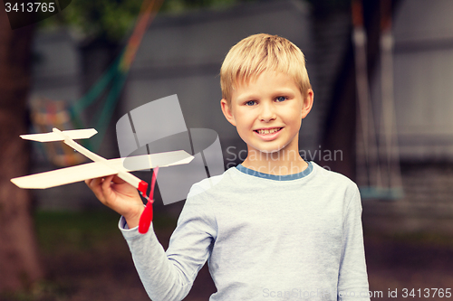 Image of smiling little boy holding a wooden airplane model