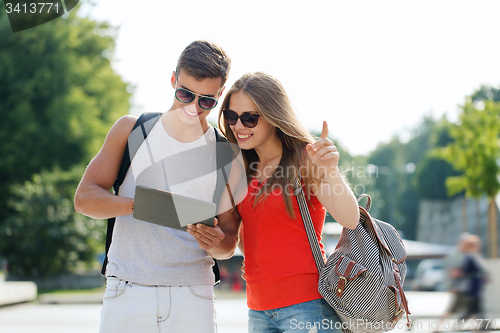 Image of smiling couple with tablet pc and backpack in city