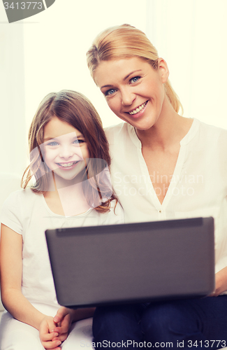 Image of smiling mother and little girl with laptop at home