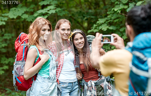 Image of friends with backpack photographing by smartphone