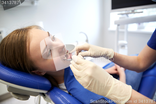 Image of female dentist checking patient girl teeth