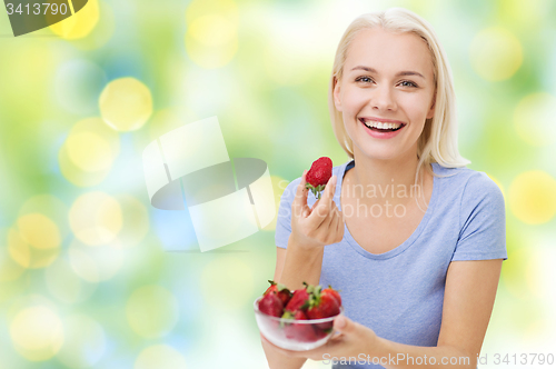 Image of happy woman eating strawberry