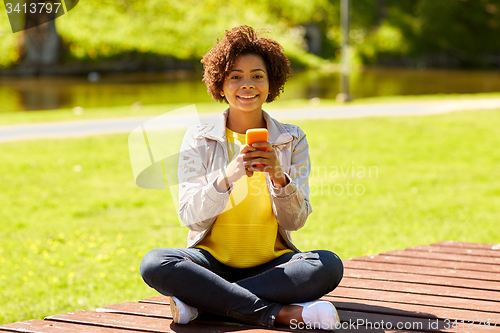 Image of happy african young woman messaging on smartphone