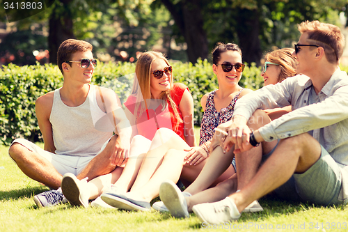 Image of group of smiling friends outdoors sitting on grass