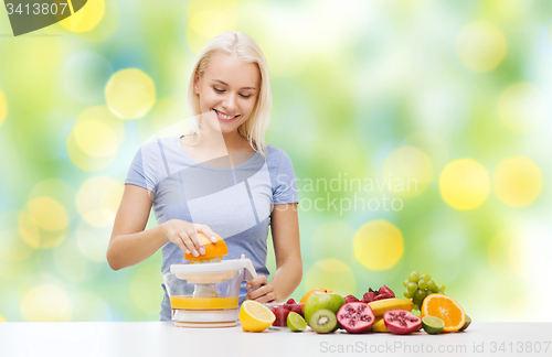 Image of smiling woman squeezing fruit juice