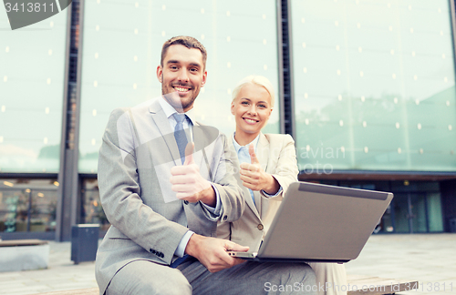 Image of smiling businesspeople with laptop outdoors