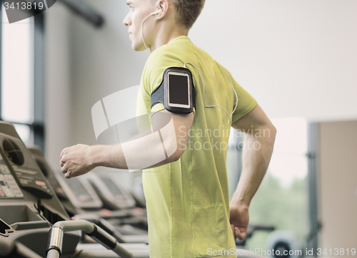 Image of man with smartphone exercising on treadmill in gym