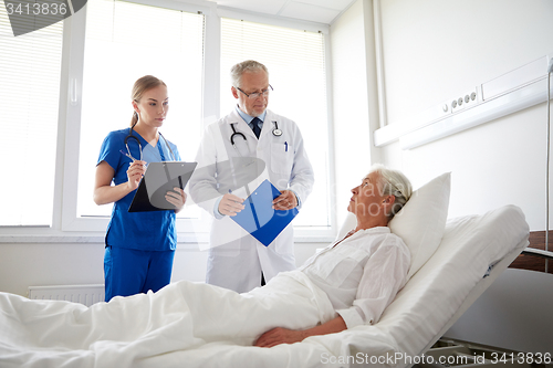 Image of doctor and nurse visiting senior woman at hospital