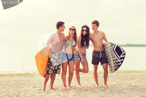 Image of smiling friends in sunglasses with surfs on beach