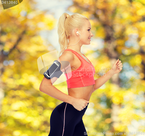 Image of sporty woman running with smartphone and earphones