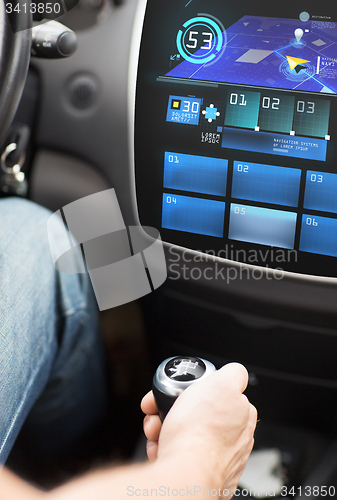 Image of hand on gearshift and car navigation system