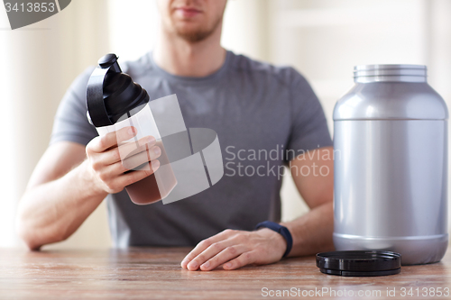 Image of close up of man with protein shake bottle and jar