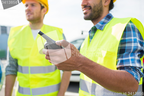 Image of close up of builders in vests with walkie talkie