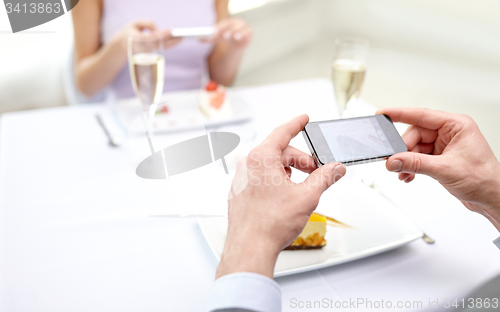 Image of close up of couple with smartphones at restaurant