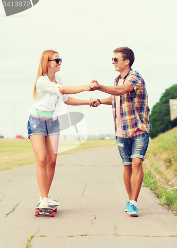 Image of smiling couple with skateboard outdoors