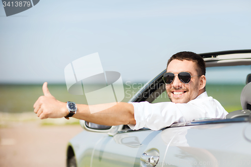 Image of happy man driving car and showing thumbs up