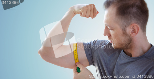 Image of close up of male hands with tape measuring bicep