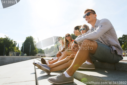 Image of group of smiling friends sitting on city street