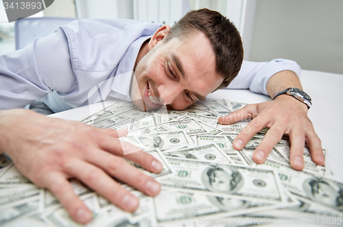 Image of happy businessman with heap of money in office