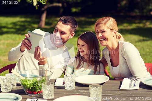 Image of happy family with tablet pc at table in garden