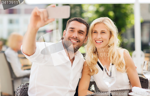 Image of happy couple taking selfie with smatphone at cafe