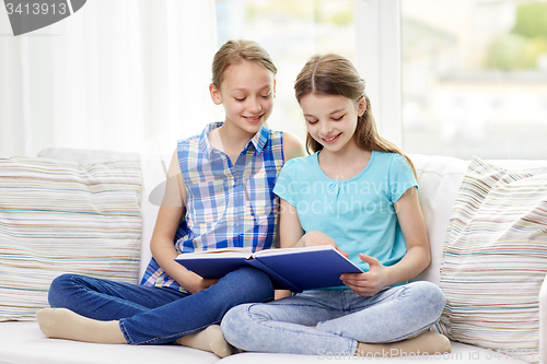 Image of two happy girls reading book at home