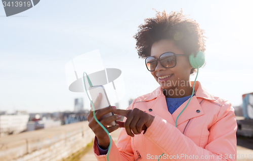 Image of happy young woman with smartphone and headphones