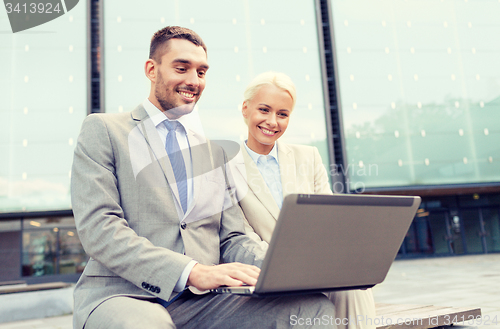 Image of smiling businesspeople with laptop outdoors