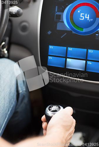 Image of hand on car gearshift and screen with volume level